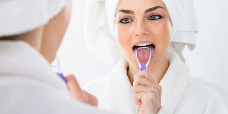woman-cleaning-her-tongue-to-avoid-bad-breath