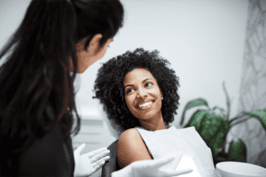 A dental patient sitting in a dental chair and smiling at a dentist