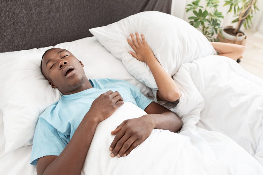 A man with sleep apnea snoring next to his wife who cannot sleep