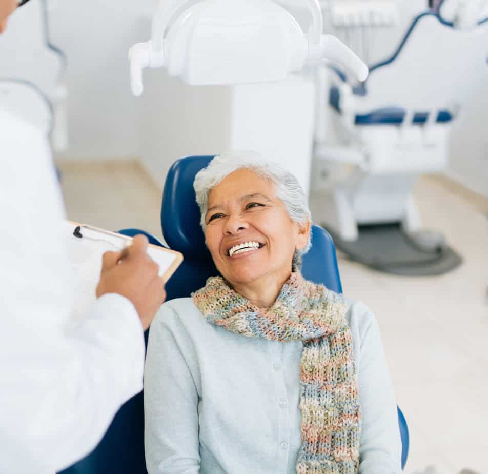 A senior woman sitting in a dental chair and smiling