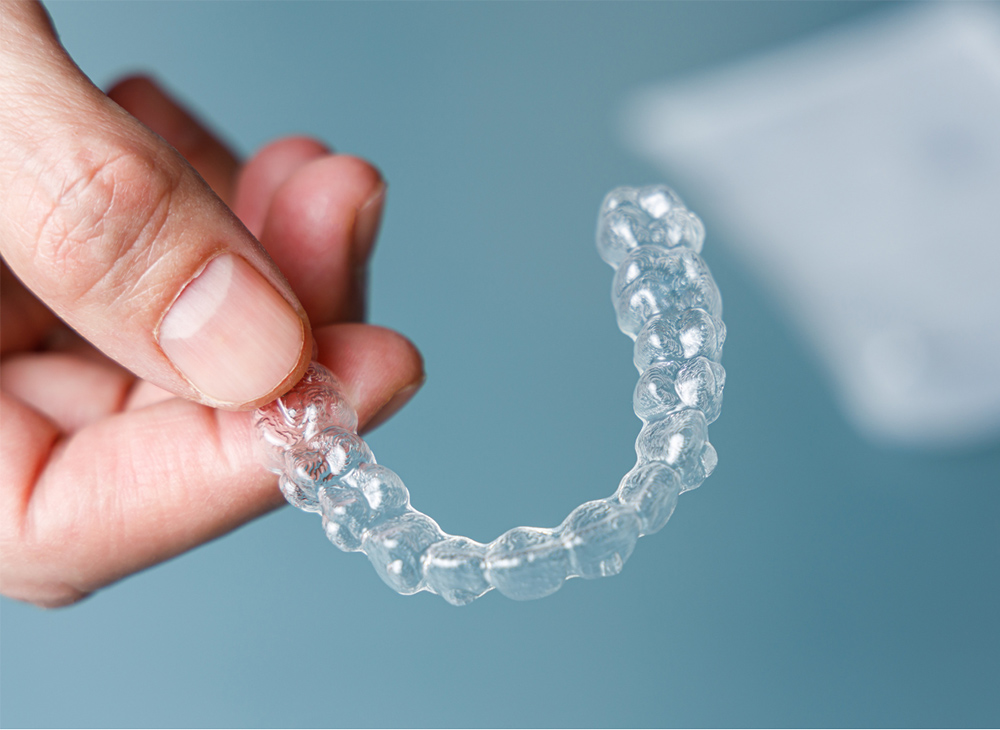 A dentist holding an Invisalign clear aligner
