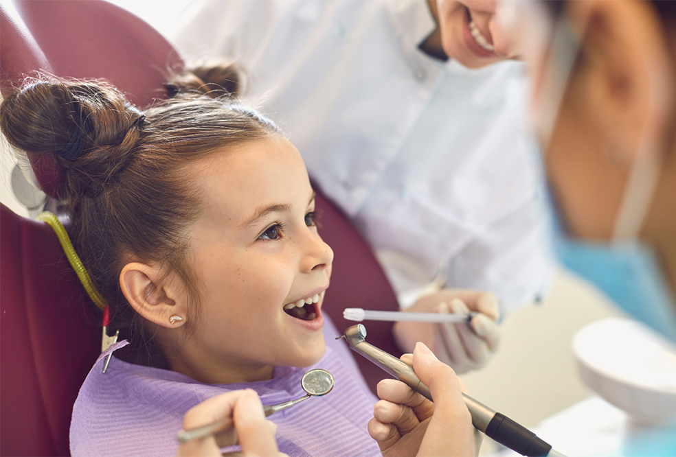 A child in a dental chair being examined by a dentist